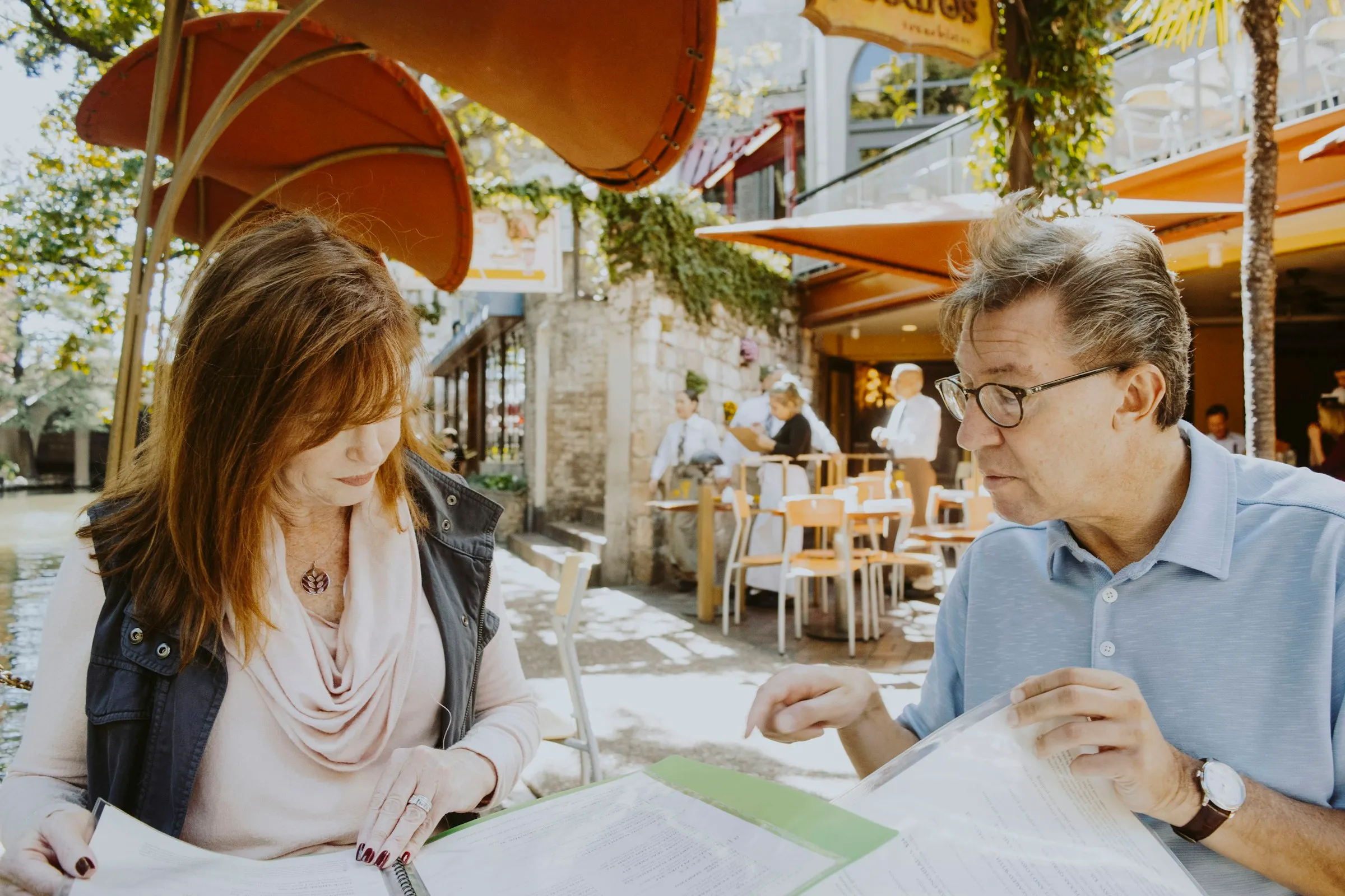 A couple reading through investment papers together at an outdoor café table